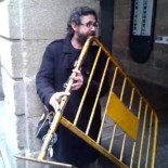 Artista callejero tocando una valla de obra como si fuese una flauta