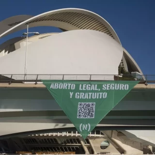 Un grupo de activistas descuelga un gran pañuelo verde en València en defensa del derecho al aborto