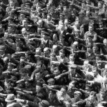 El hombre cruzado de brazos en medio del saludo nazi